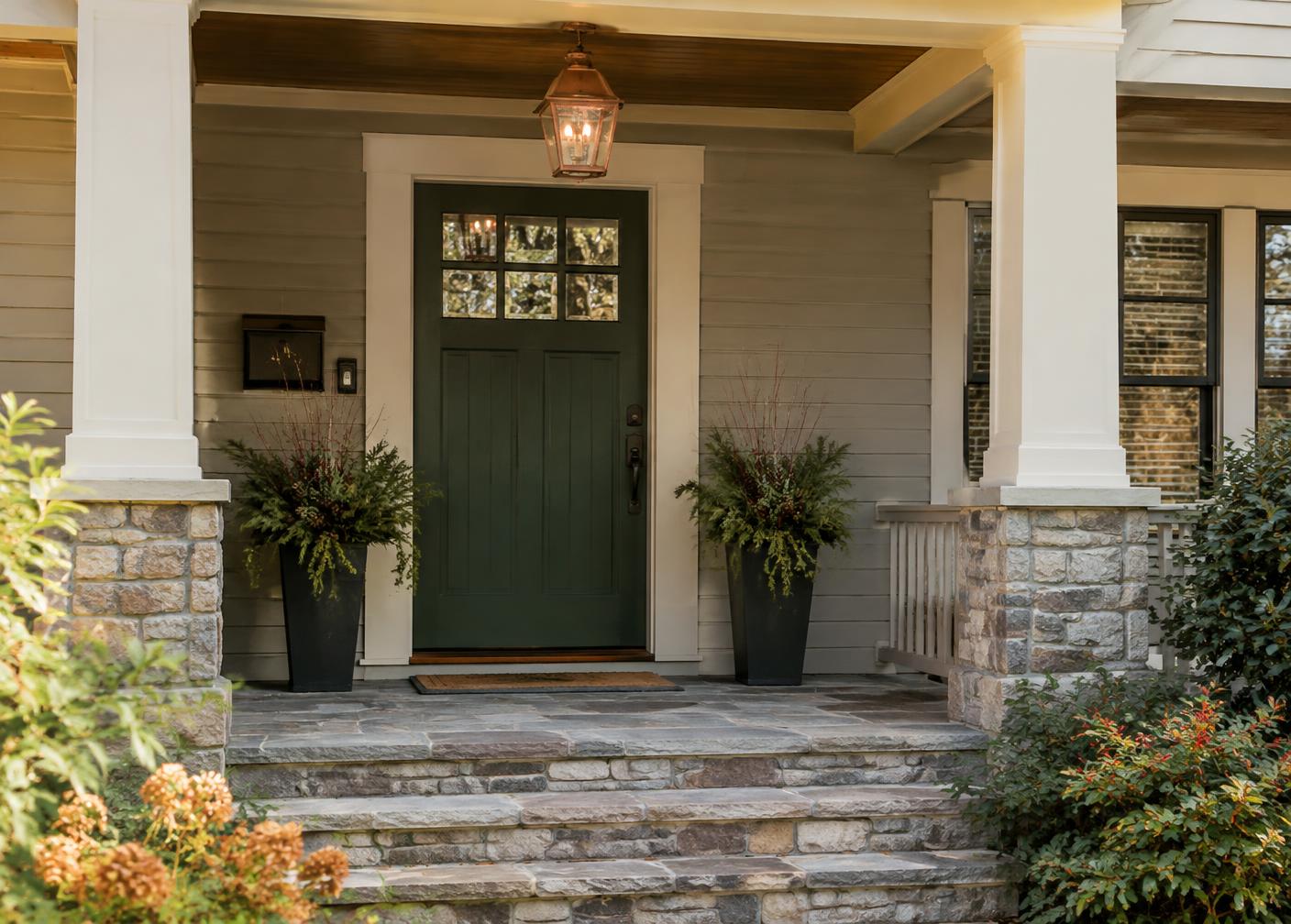 Craftsman porch with stone steps and a green front door